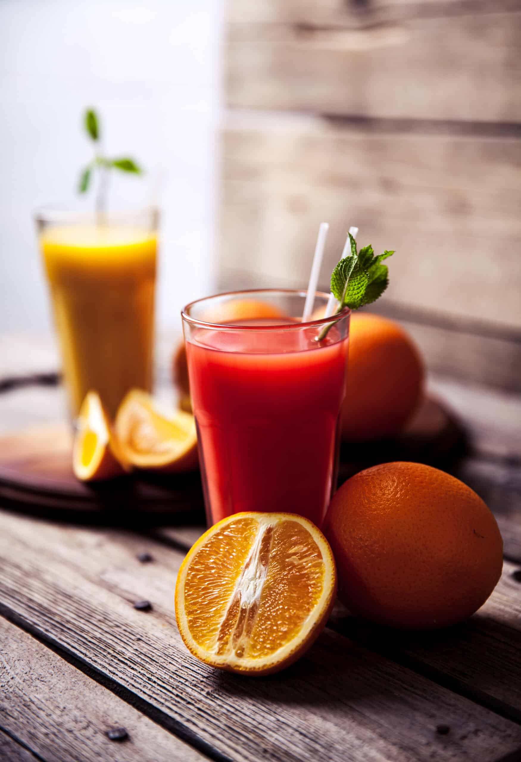 Orange juice in glass with mint, fresh fruits on wooden background a